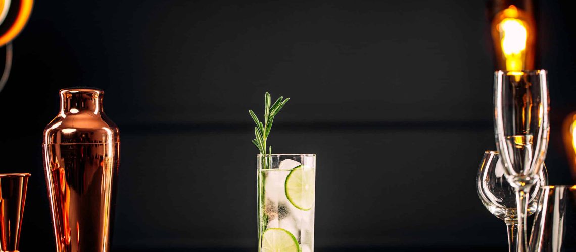 Fresh gin tonic cocktail with rosemary and lime on the wooden table